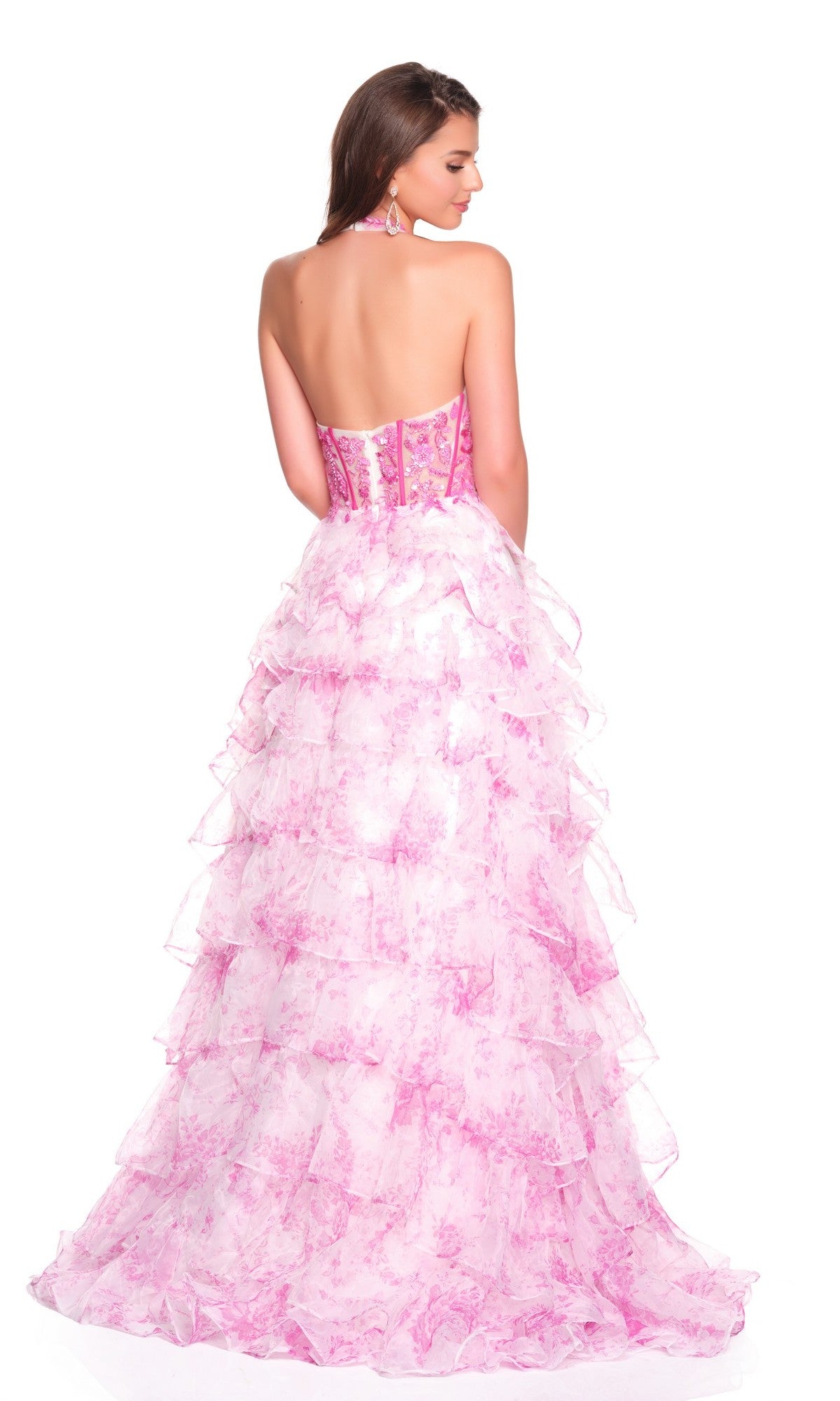 A woman in the Dave and Johnny 12766 long prom dress, featuring a strapless pink and white ruffled corset bodice and chiffon a-line skirt, stands with her back to the camera, highlighting its tiered layers.